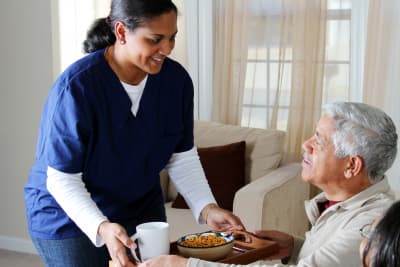 female caregiver serving food to senior man